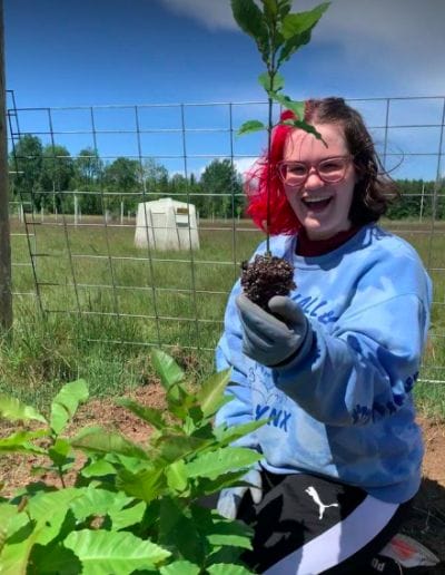 2021 intern Olivia plants a sapling