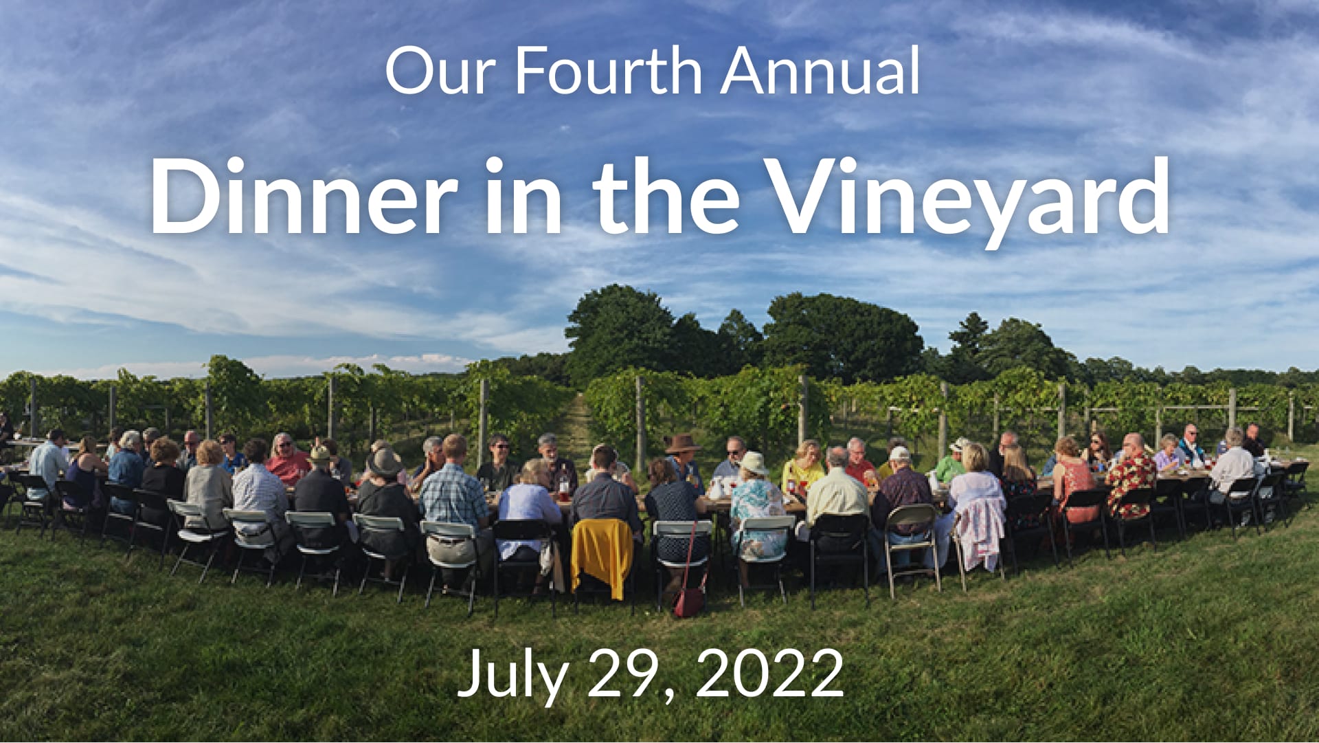 People seated at a long table in front of vineyard. Text reads: "Our Fourth Annual Dinner in the Vineyard, July 29, 2022"